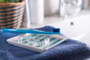 Toothbrush, floss, and clear aligner on clean bathroom counter